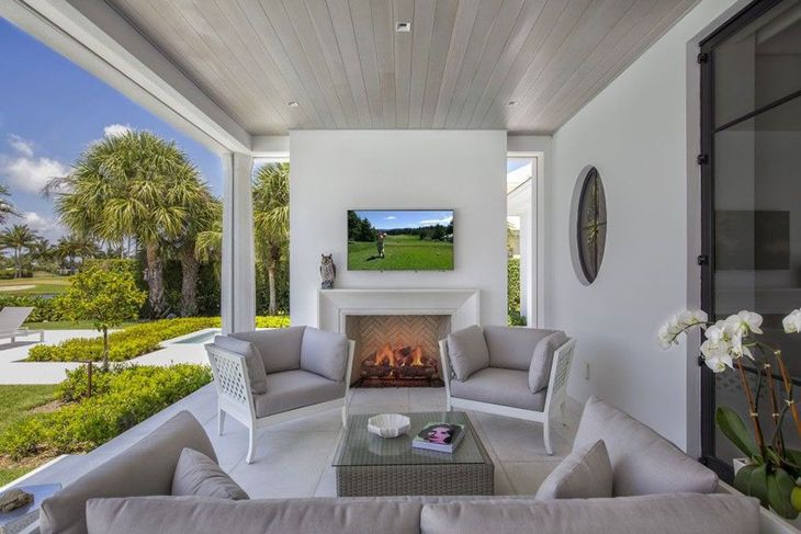 A living room with an outdoor fireplace and a television on the wall
