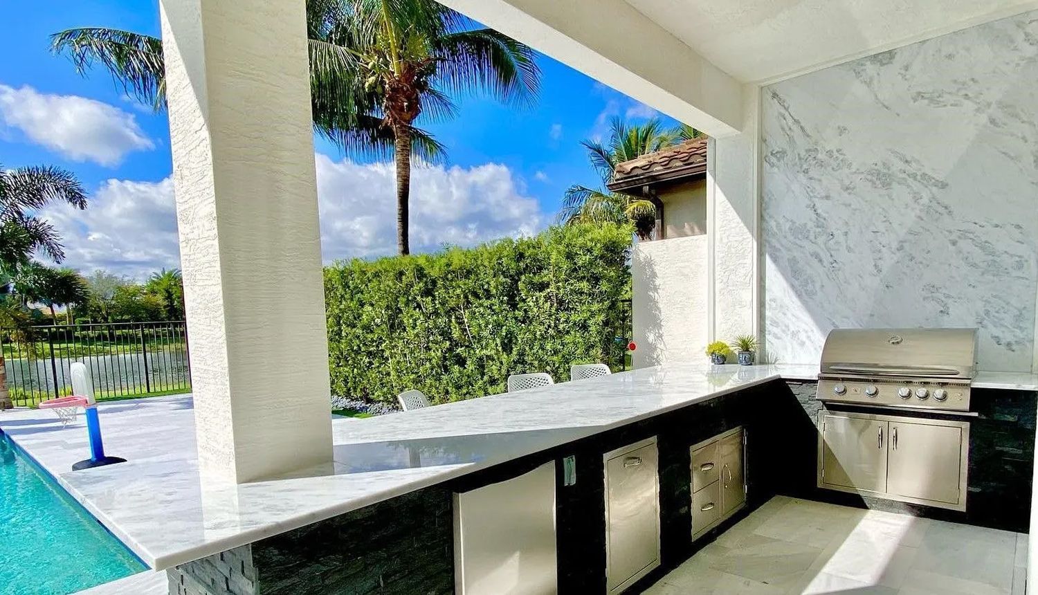 A kitchen with a grill and a swimming pool in the background.