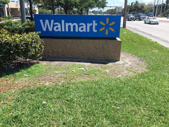 A walmart sign is sitting in the grass on the side of the road