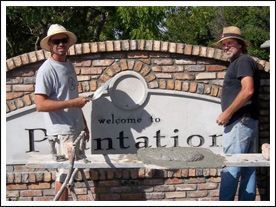 Two men are standing in front of a sign that says welcome to plantation