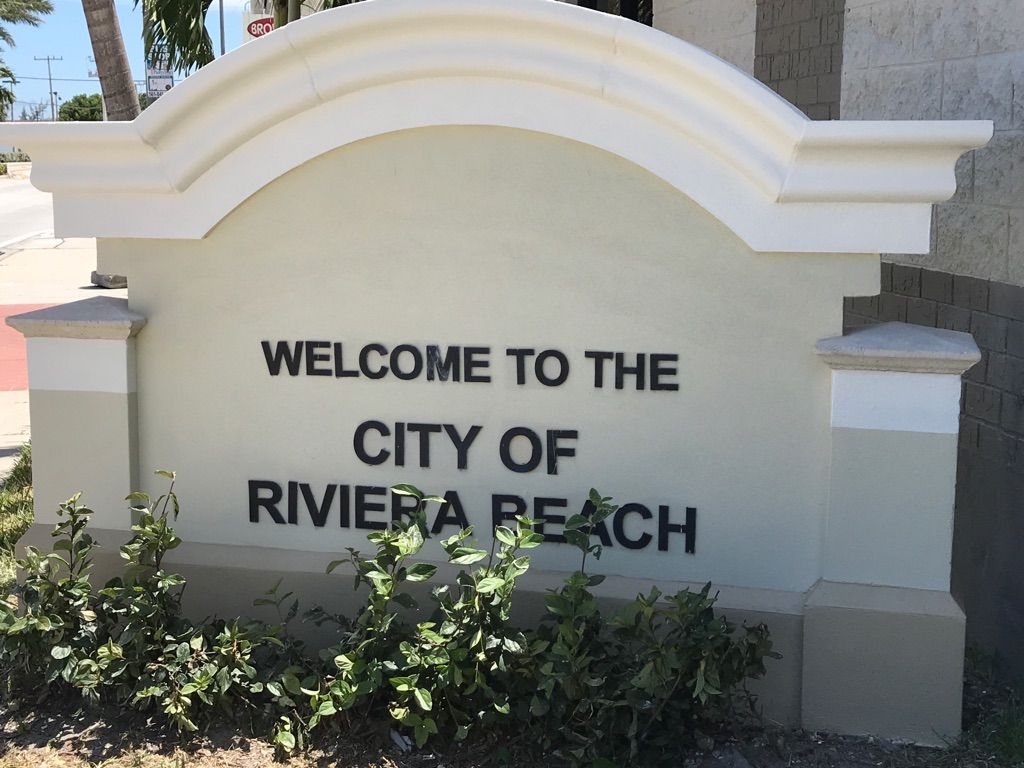 A white sign that says welcome to the city of riviera beach