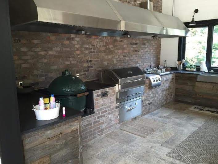 A kitchen with a grill and a green egg in it.