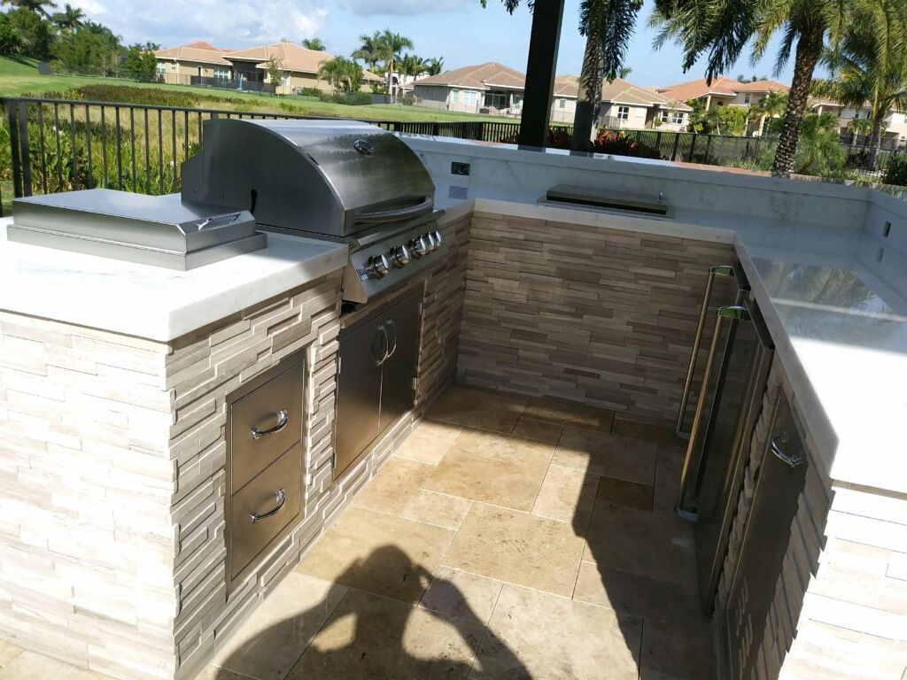 An outdoor kitchen with a grill and a brick wall