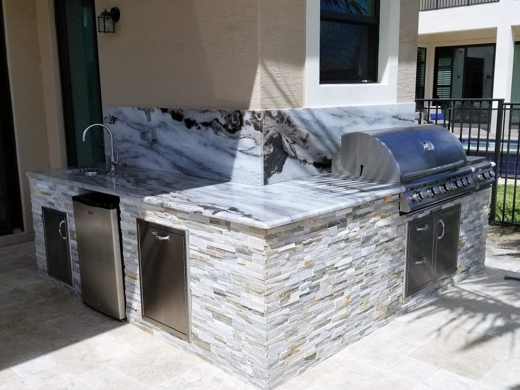 A large outdoor kitchen with a grill , sink , and dishwasher.