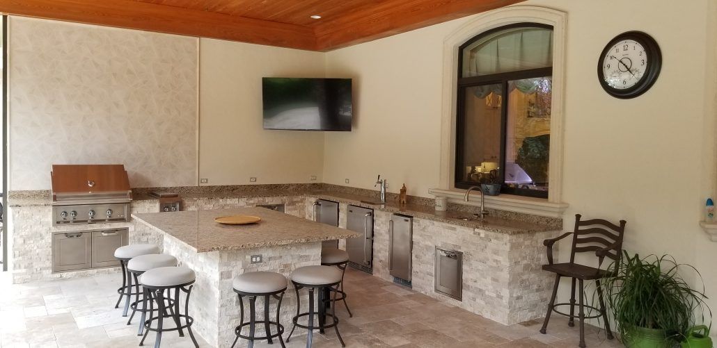 A kitchen with a large table and stools and a clock on the wall.