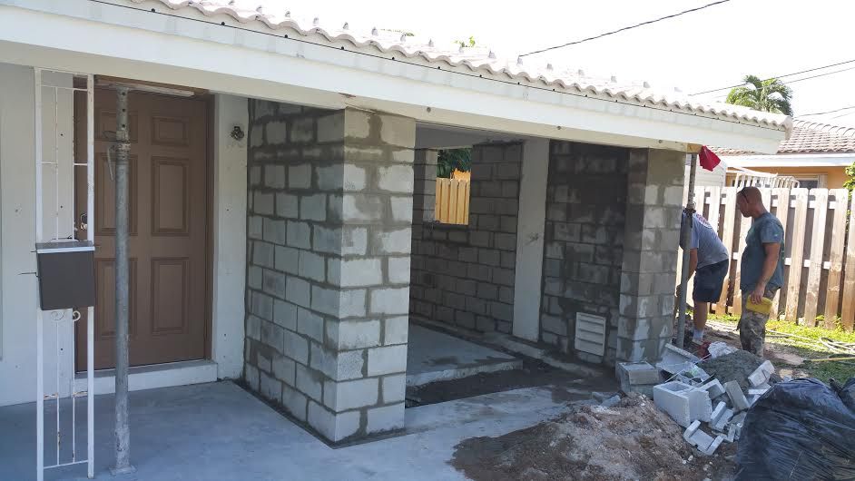 A couple of men are standing in front of a house.