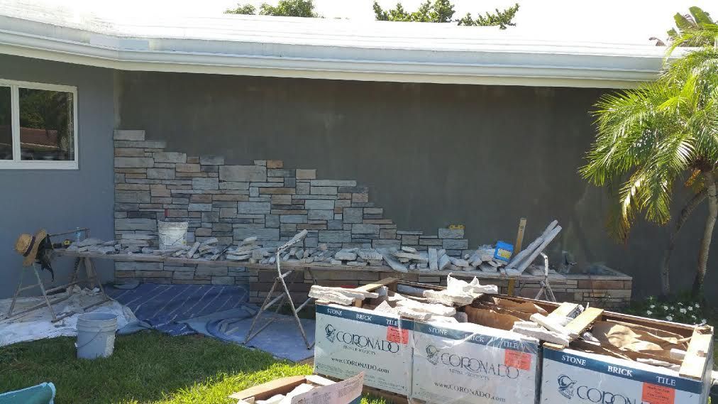 A stone wall is being built on the side of a house.