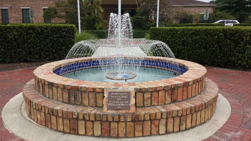 A fountain made of bricks and tiles is in front of a building.