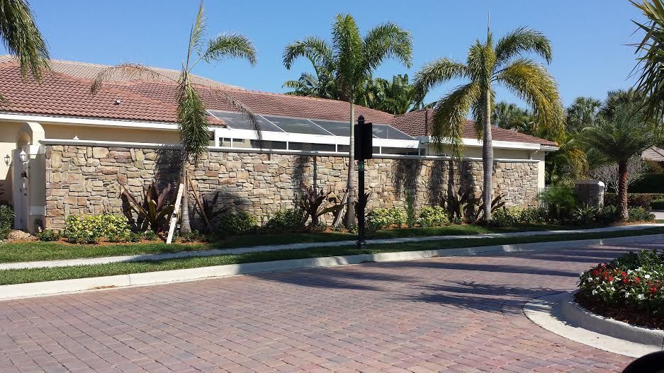 A brick driveway leading to a house with palm trees in the background