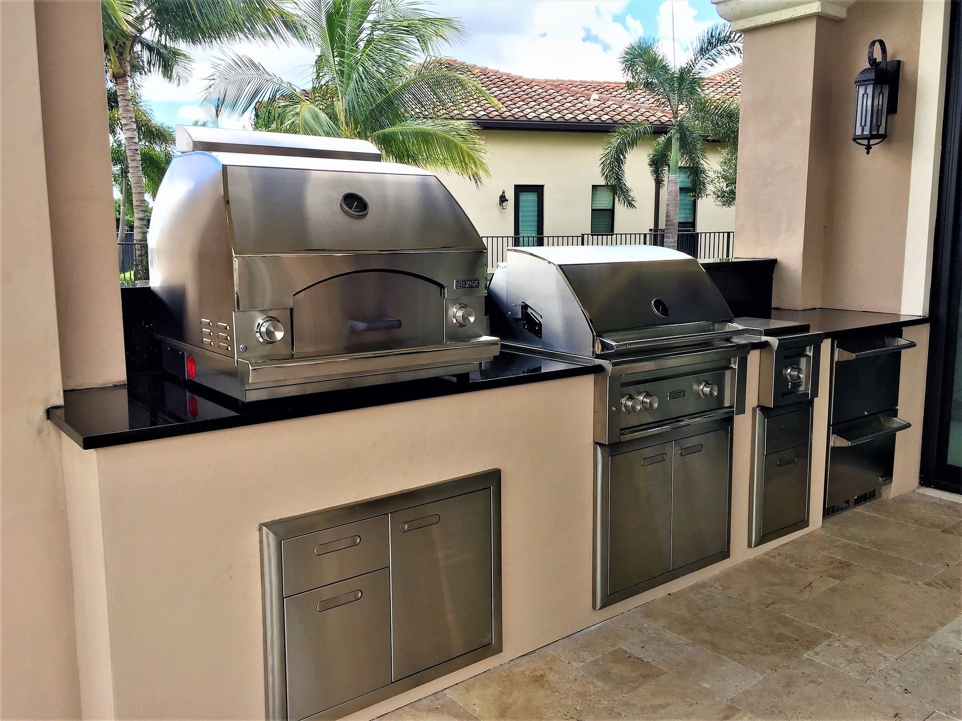 An outdoor kitchen with stainless steel appliances and a pizza oven