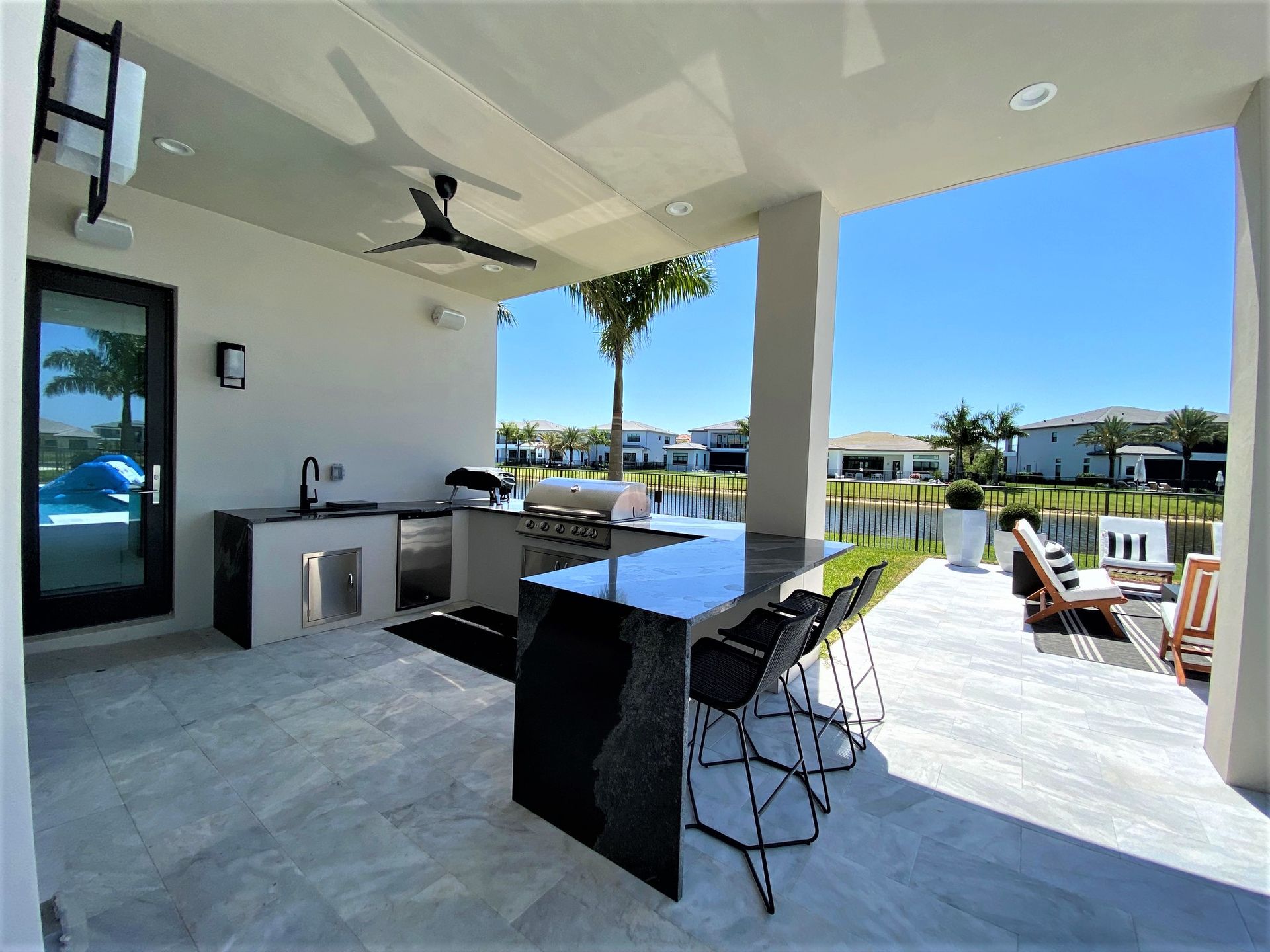 Elegant outdoor kitchen with granite countertops and seating area overlooking a waterfront in Parkland, FL.