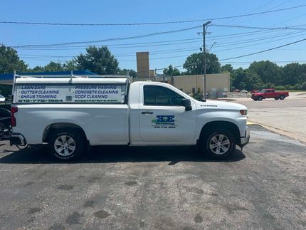 White utility truck with logo parked in a sunny lot beside a road under blue sky