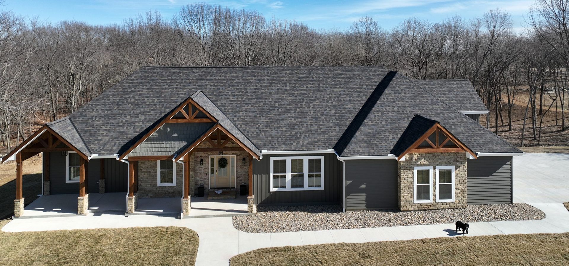A gray house with a stone facade and wooden accents, a porch, and a walkway.