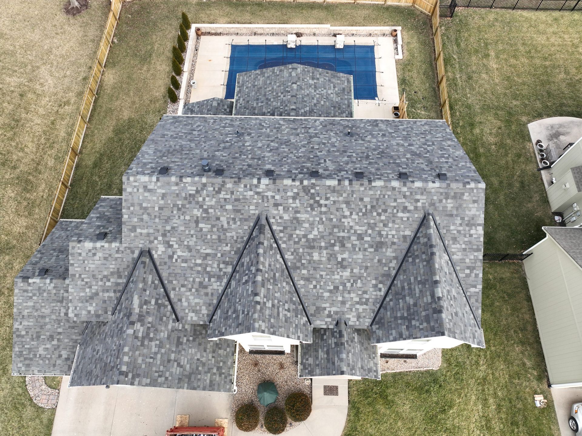 Overhead view of a house with a gray shingle roof, pool, and backyard.