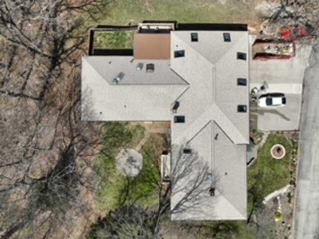 Overhead view of a house with a complex roof and a driveway with a white car.