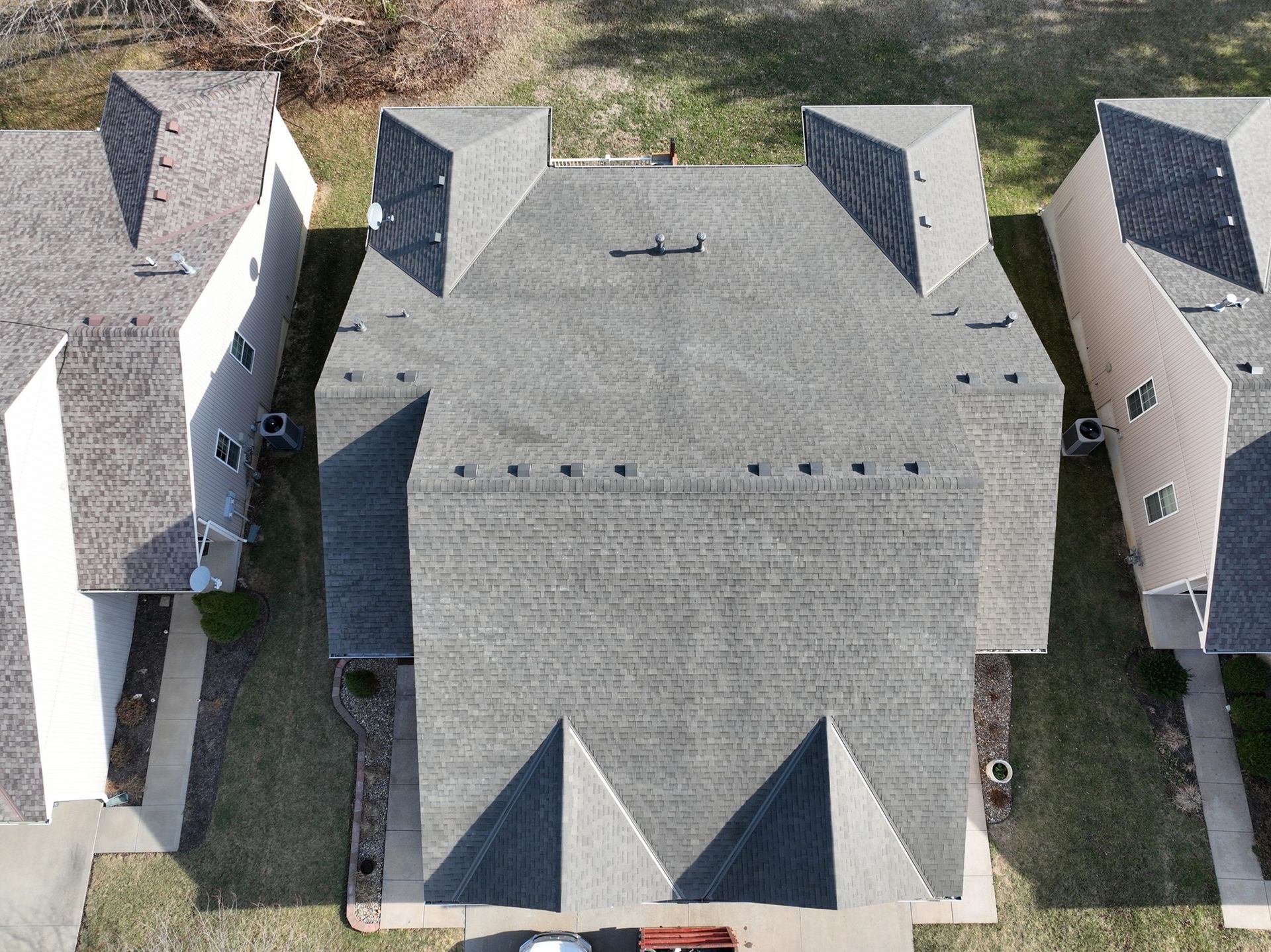Overhead view of a gray asphalt shingle roof on a townhouse. Other townhouses are on either side.