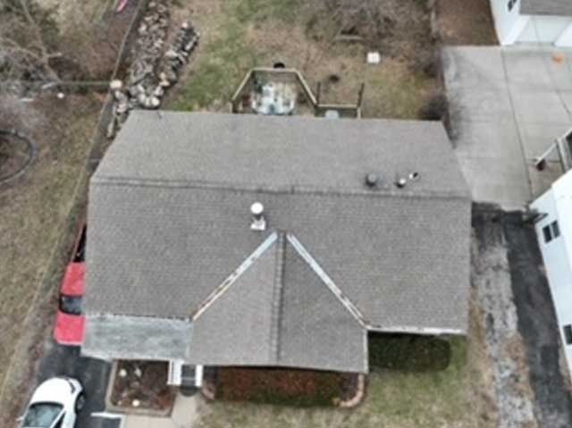 Overhead view of a house with a gray roof, small garden, two cars, and a driveway.