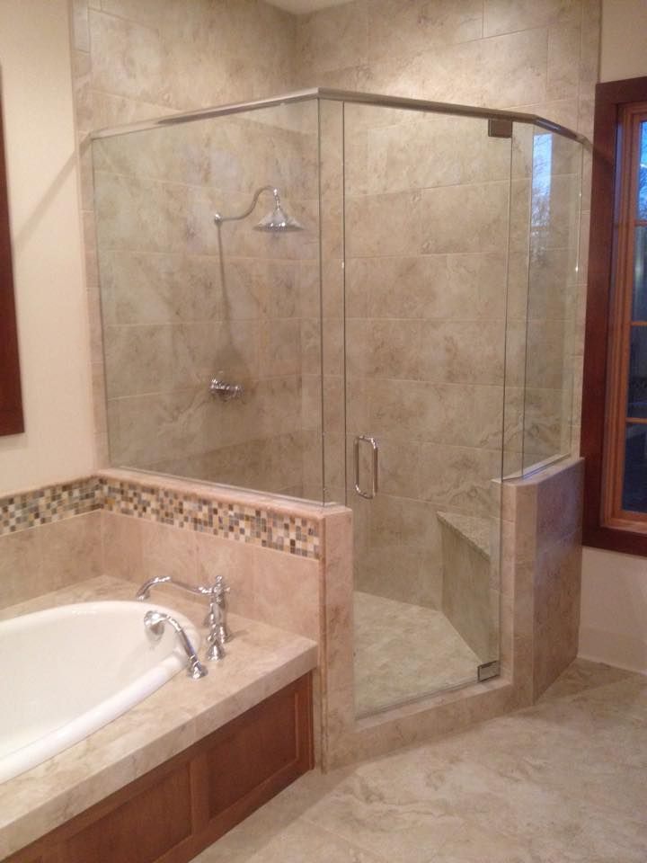 Spacious bathroom with glass shower, built-in bench, and adjacent bathtub with wooden accents.