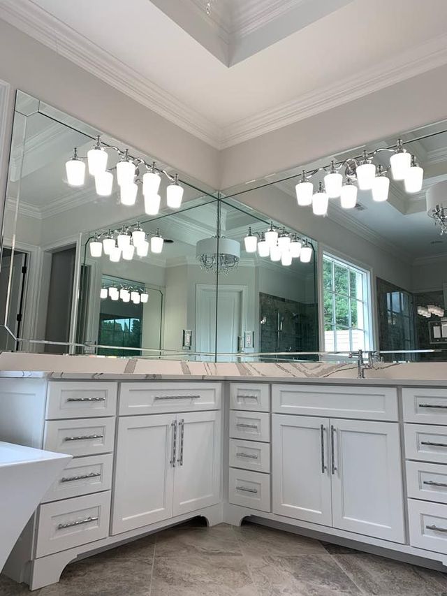White bathroom vanity with marble countertop and mirrored wall.