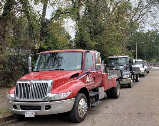 A classic, dusty, gray sports car being transported on a white tow truck.