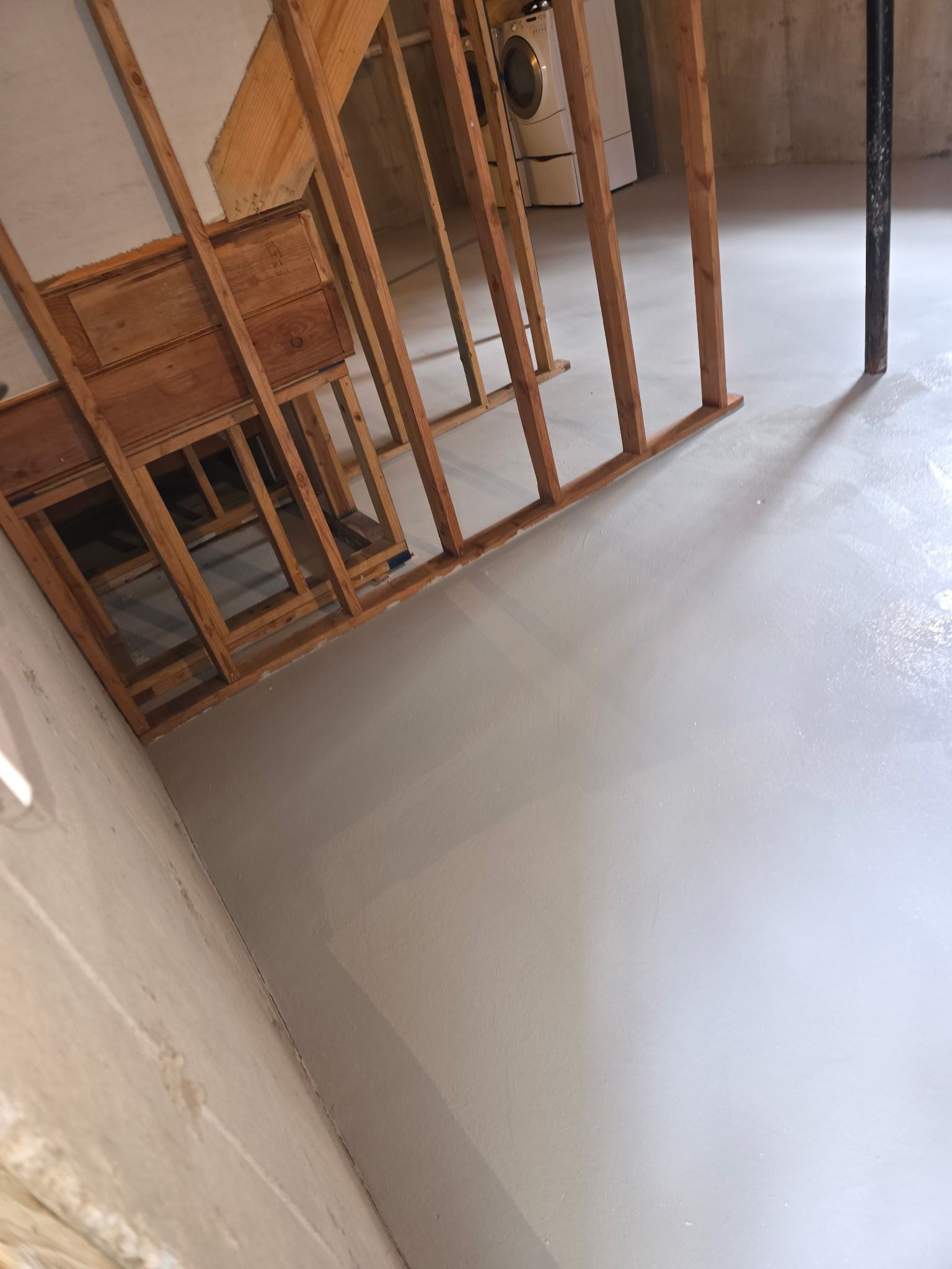 Interior with unfinished wooden framing and a smooth gray floor