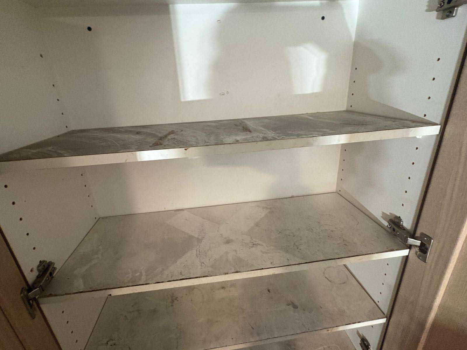 An interior view of a white cabinet with three shelves featuring a gray, faux-marble finish.