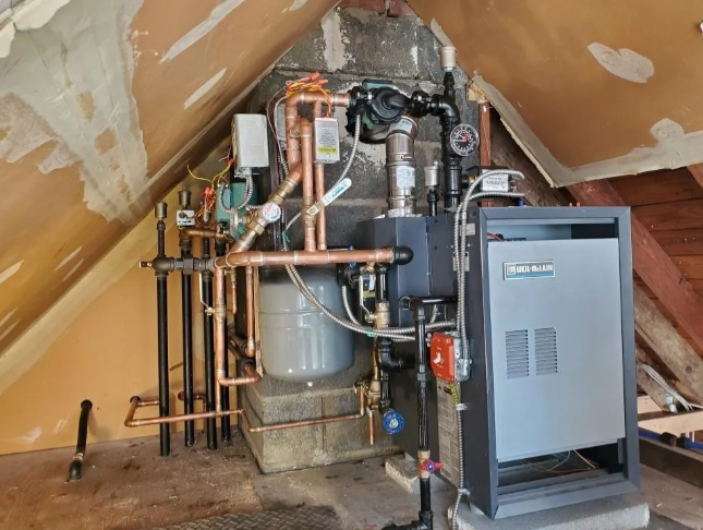 Heating system with copper pipes, tank, and a grey boiler in an attic.