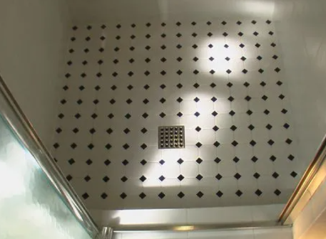 Shower floor with white and black diamond-shaped tiles, drain in the center.