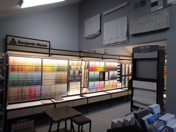 Benjamin Moore paint store exterior with glass door, brown siding, and sign.