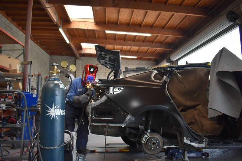 A man is welding a car in a garage.