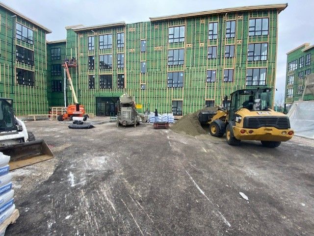a large building under construction with a lot of machinery in front of it .