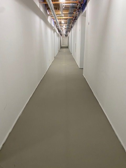 a long hallway with white walls and a gray floor in a building .