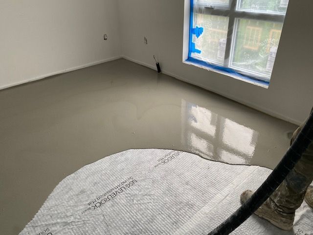 a person is laying concrete in a room with a window