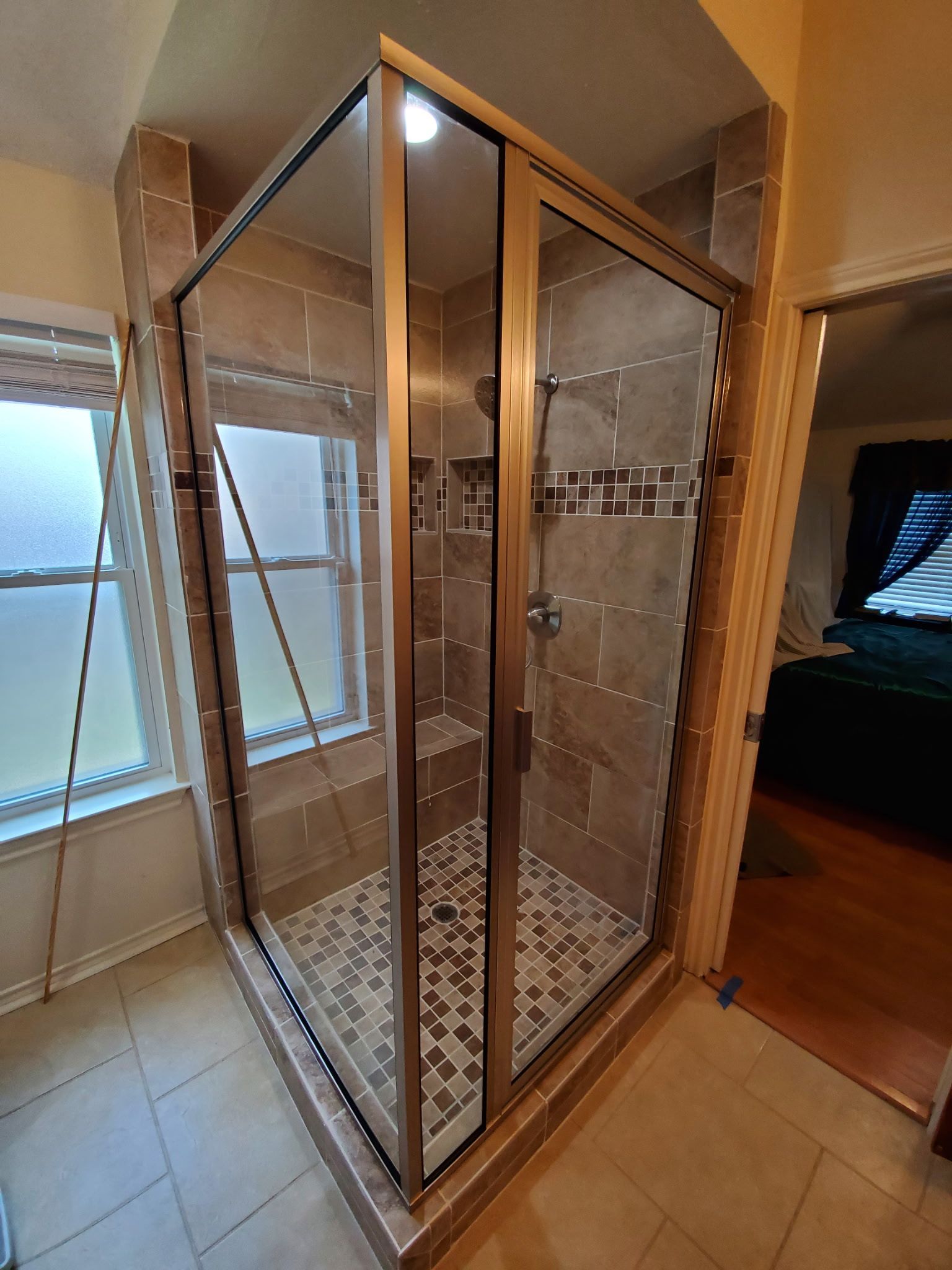 Corner shower enclosure with glass doors, tiled walls, and patterned floor.