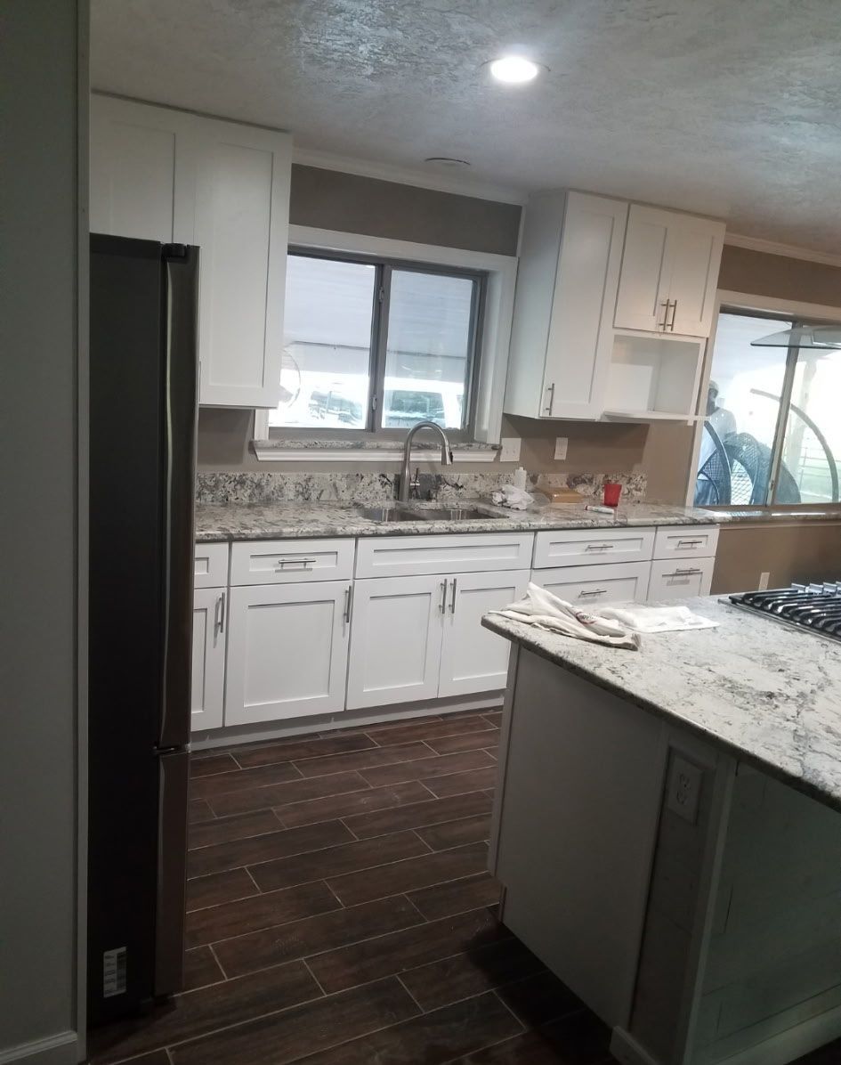 White kitchen with granite countertops, stainless steel appliances, and dark wood floors.