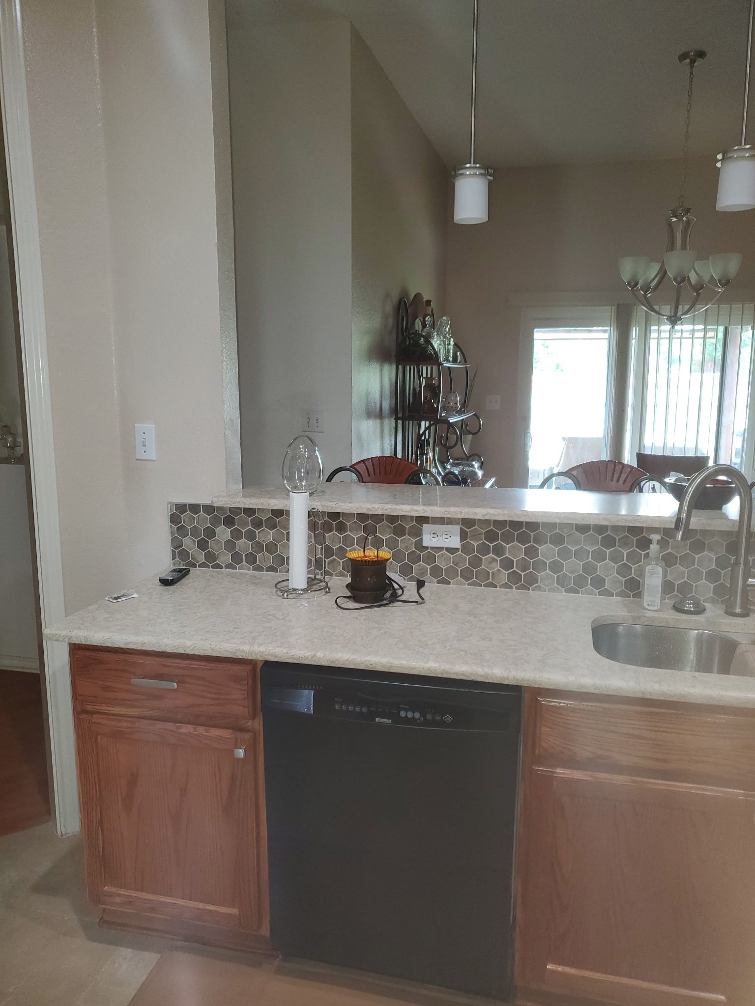 Kitchen with light countertops, brown cabinets, and a backsplash with a dark-colored mosaic.