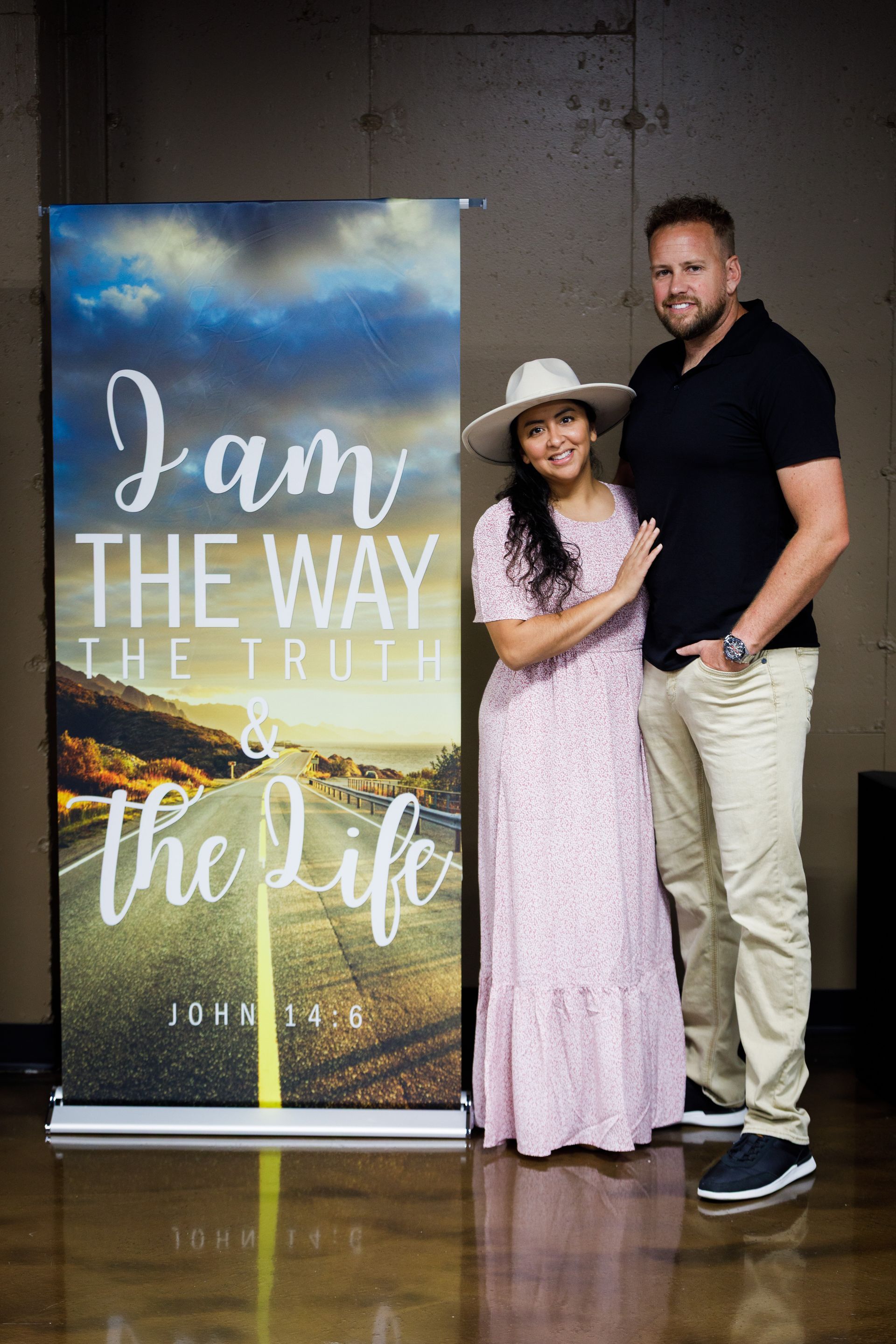 A couple stands by a banner that reads I am the way, the truth, the life.