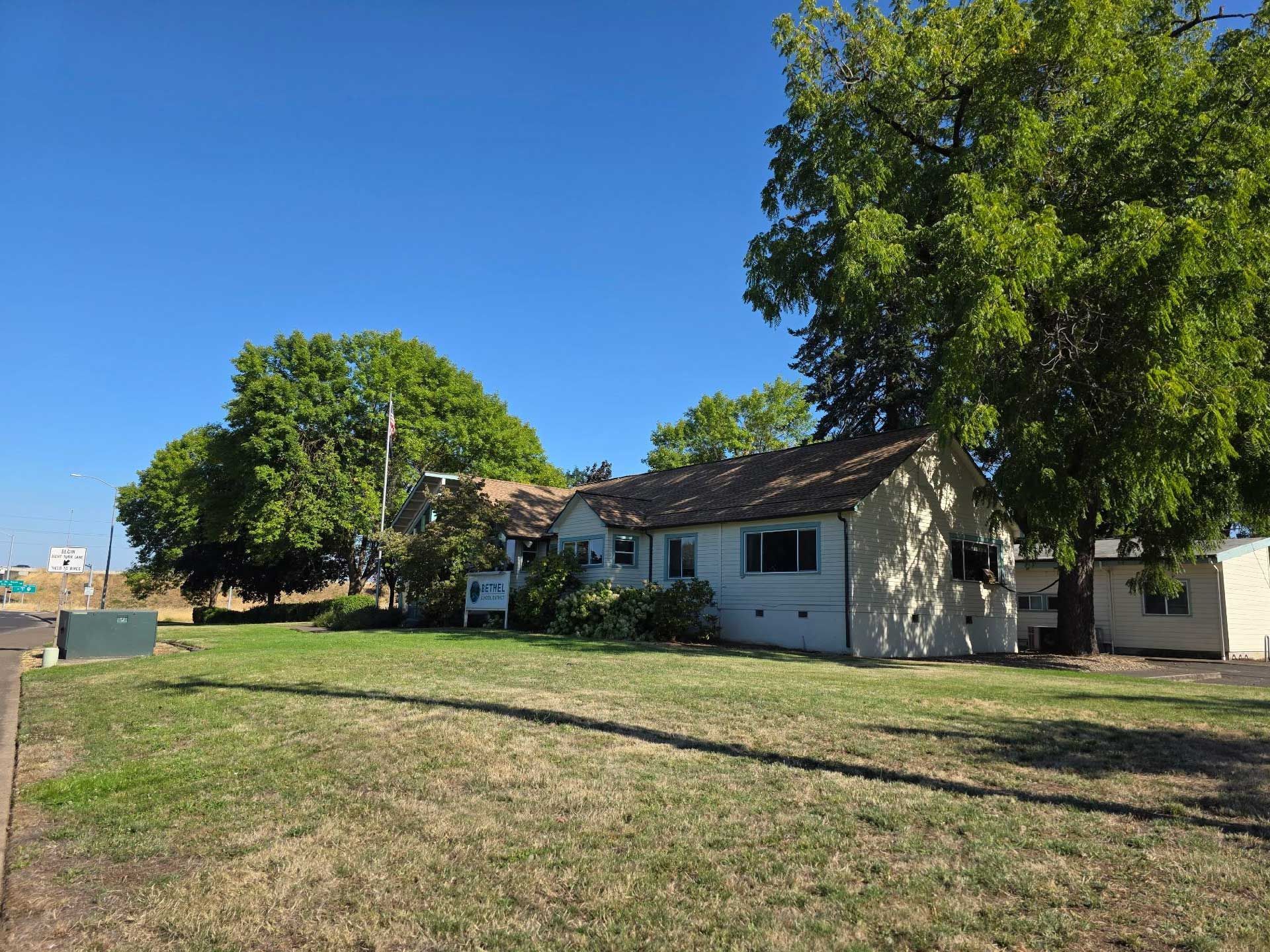 a low, light-colored building with a dark roof under a bright blue sky