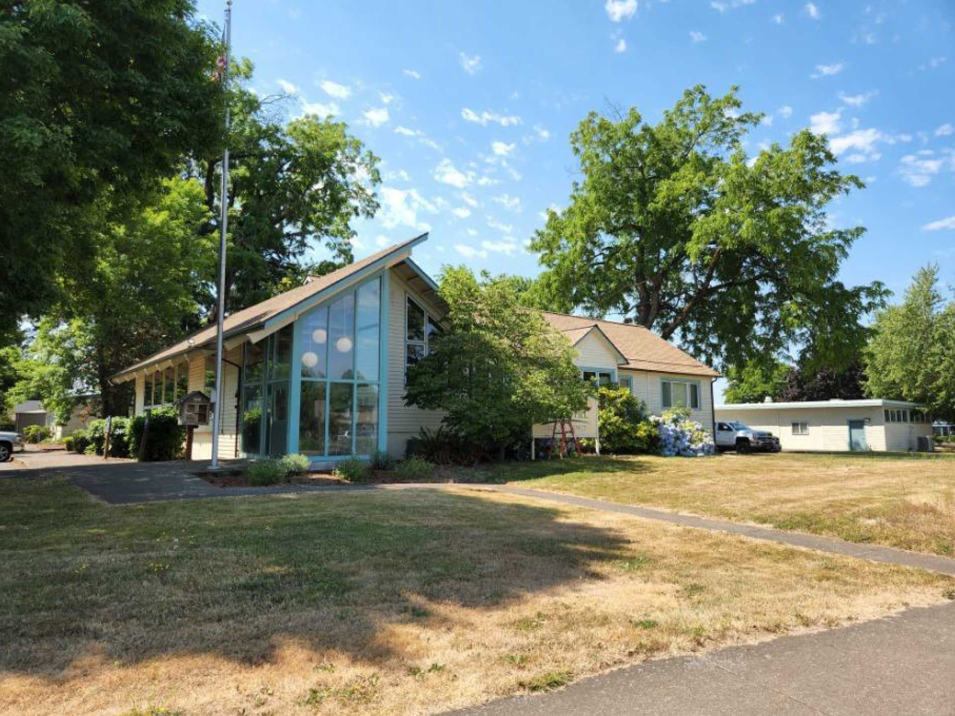 two buildings with a glass-fronted angled roof and a tan-colored house
