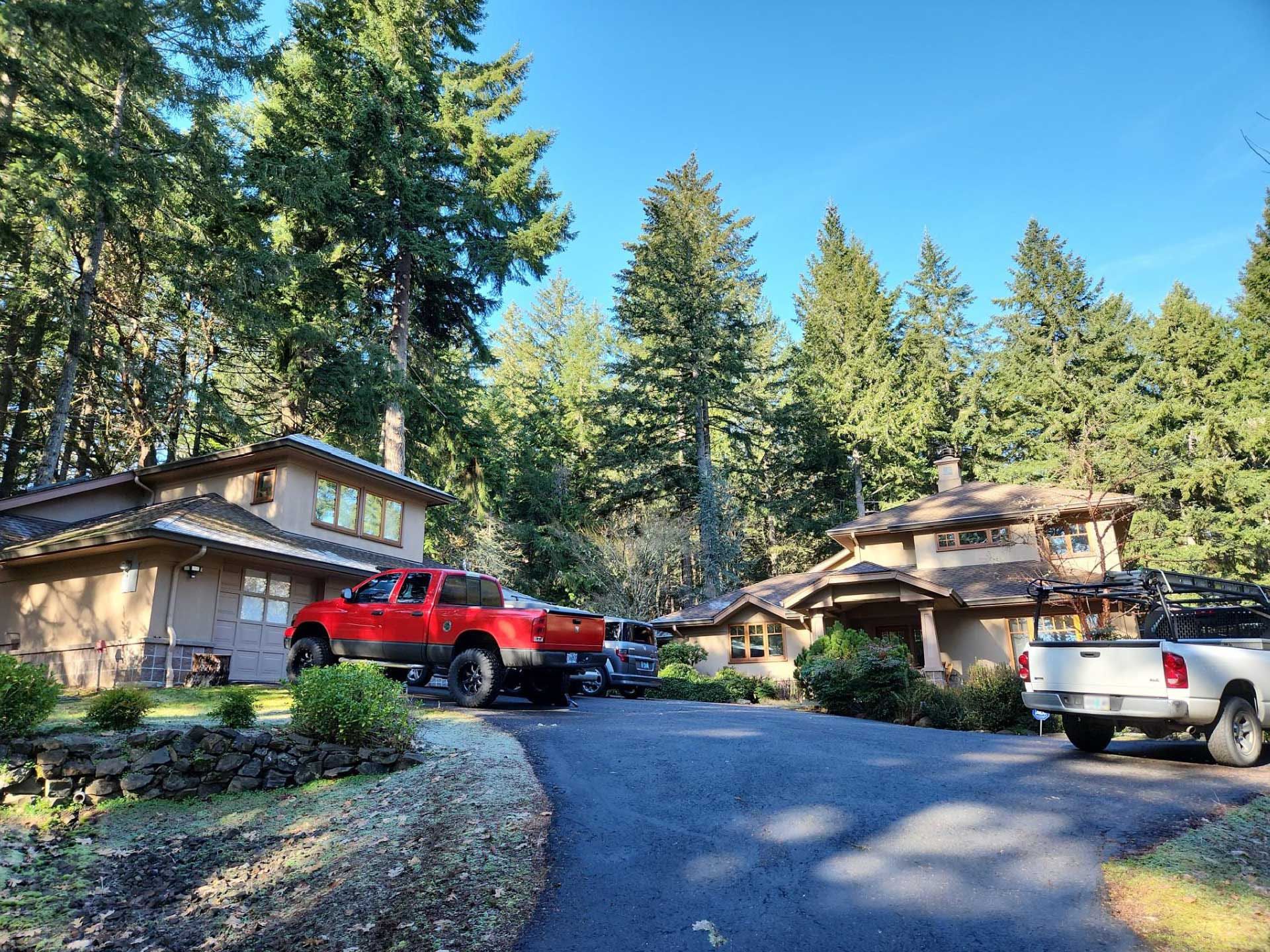 a house with a driveway, surrounded by trees, a white truck is parked
