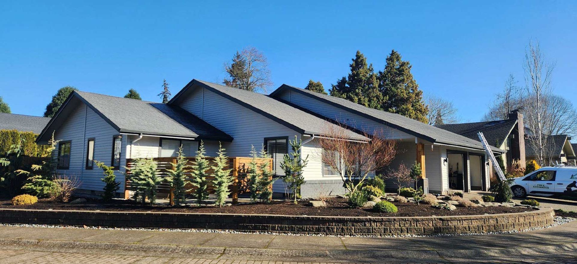 a modern home under construction, gray roof and siding, landscaping in front
