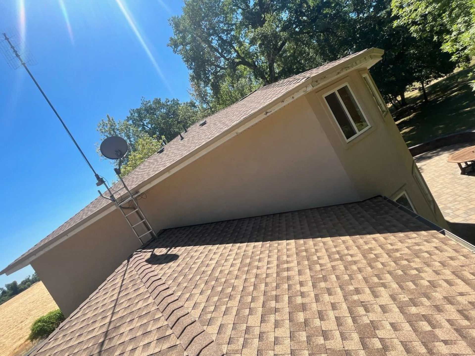tan house with brown shingle roof, satellite dish, and antenna