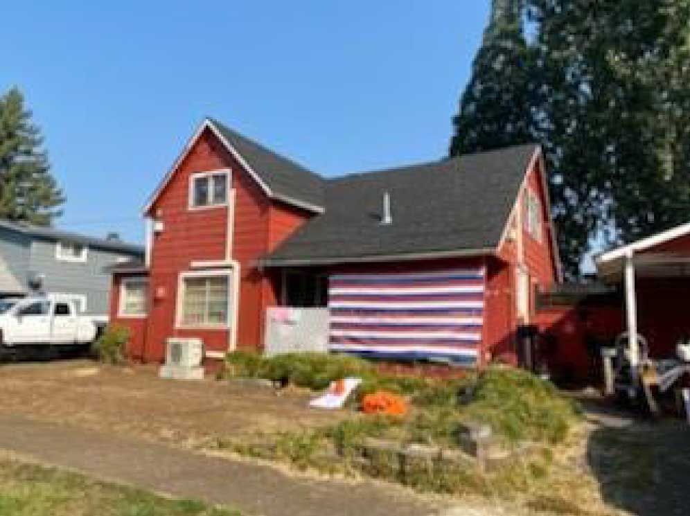 red house with black roof and American flag-themed awning