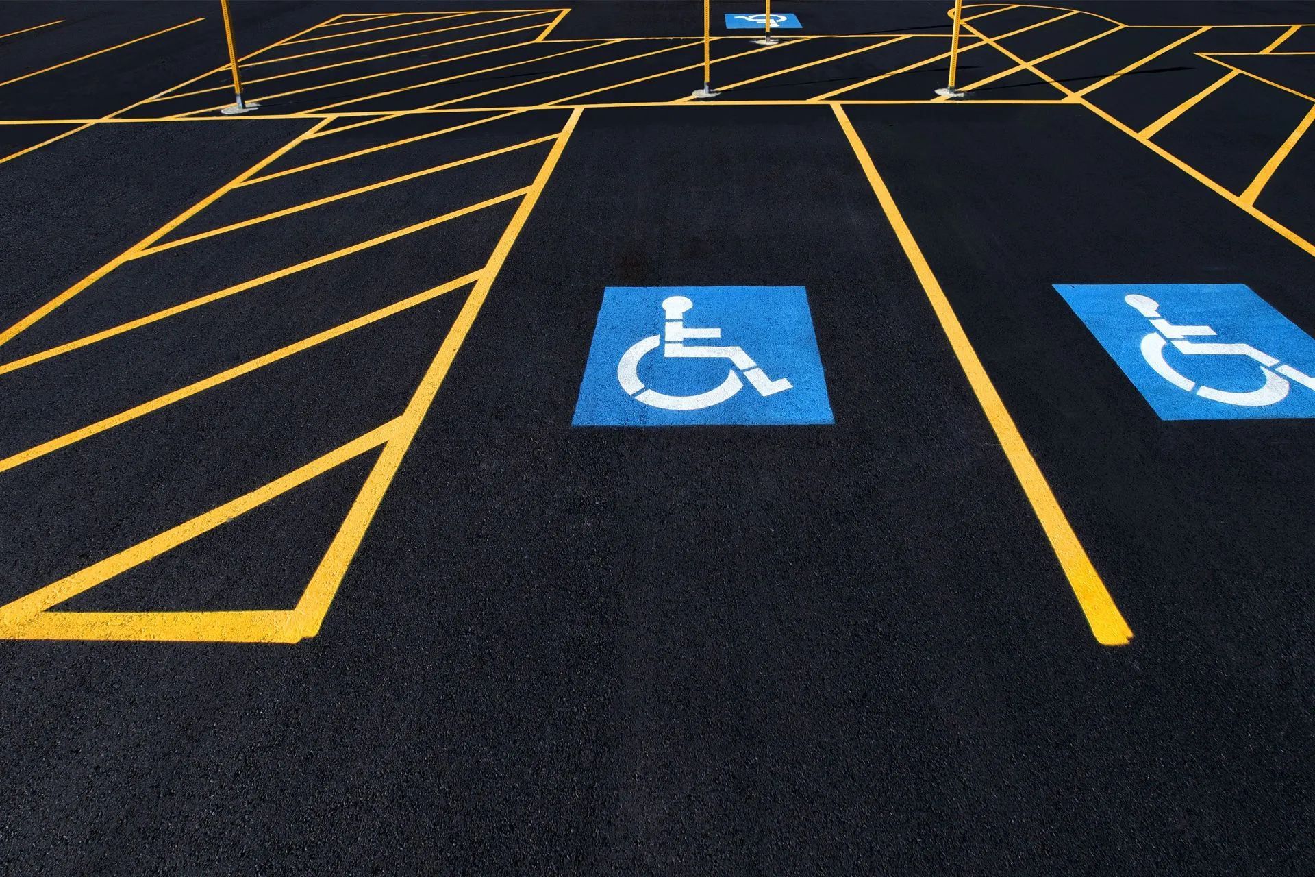 Parking lot with two accessible parking spaces marked with blue wheelchair symbols and yellow lines.