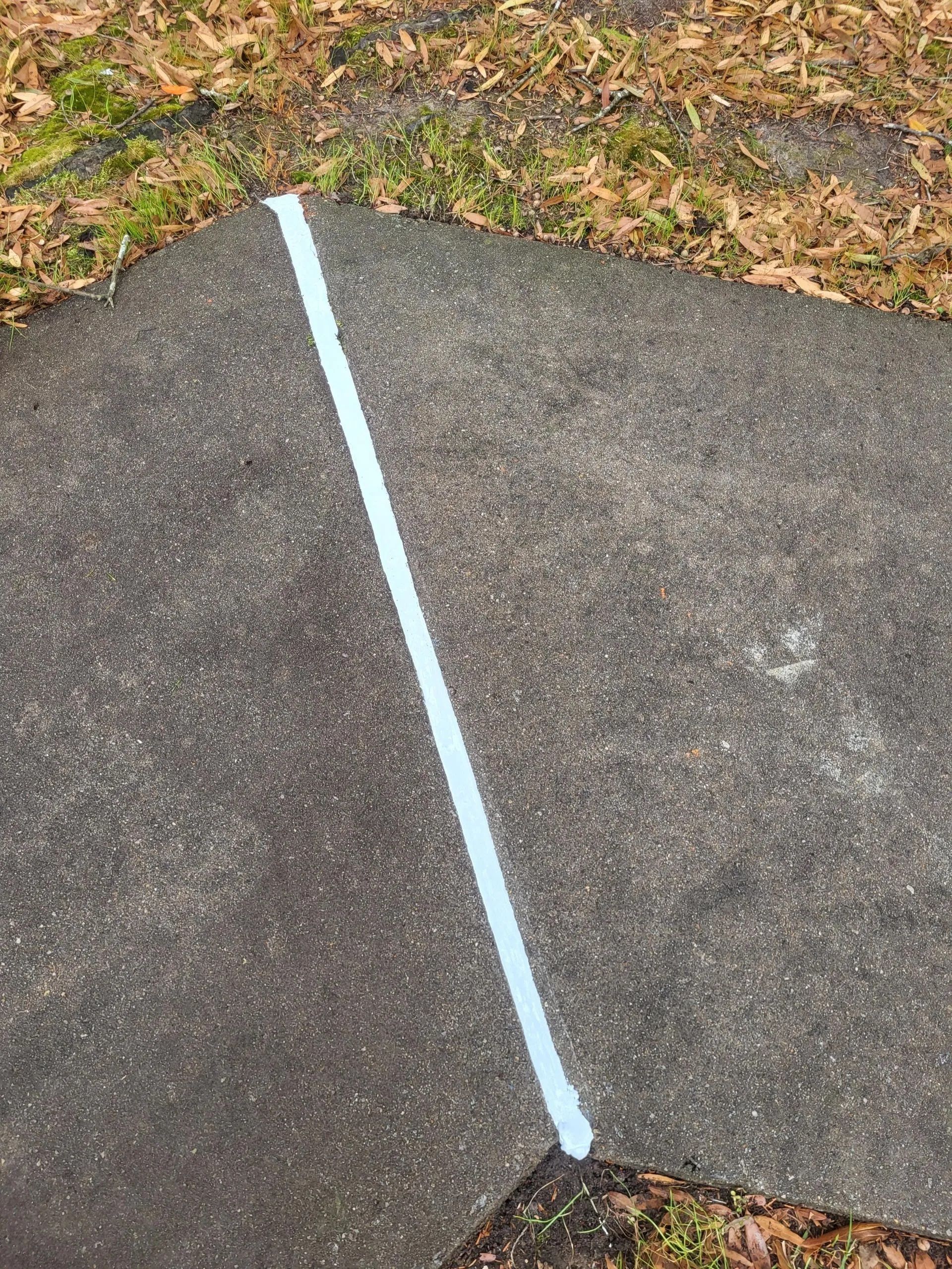White line painted diagonally across dark pavement.