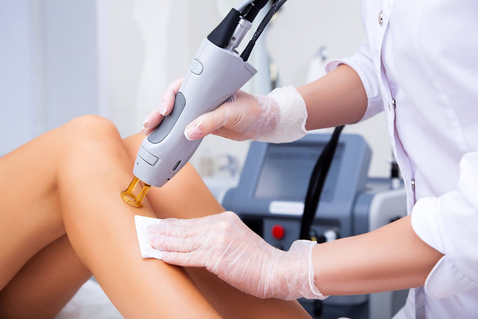 A woman is getting a laser hair removal treatment on her legs.