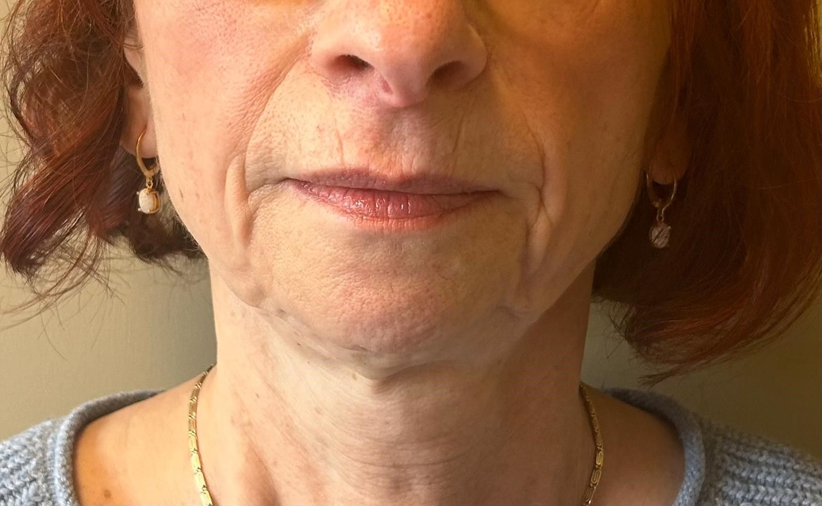 A close up of a woman 's face with wrinkles and earrings.