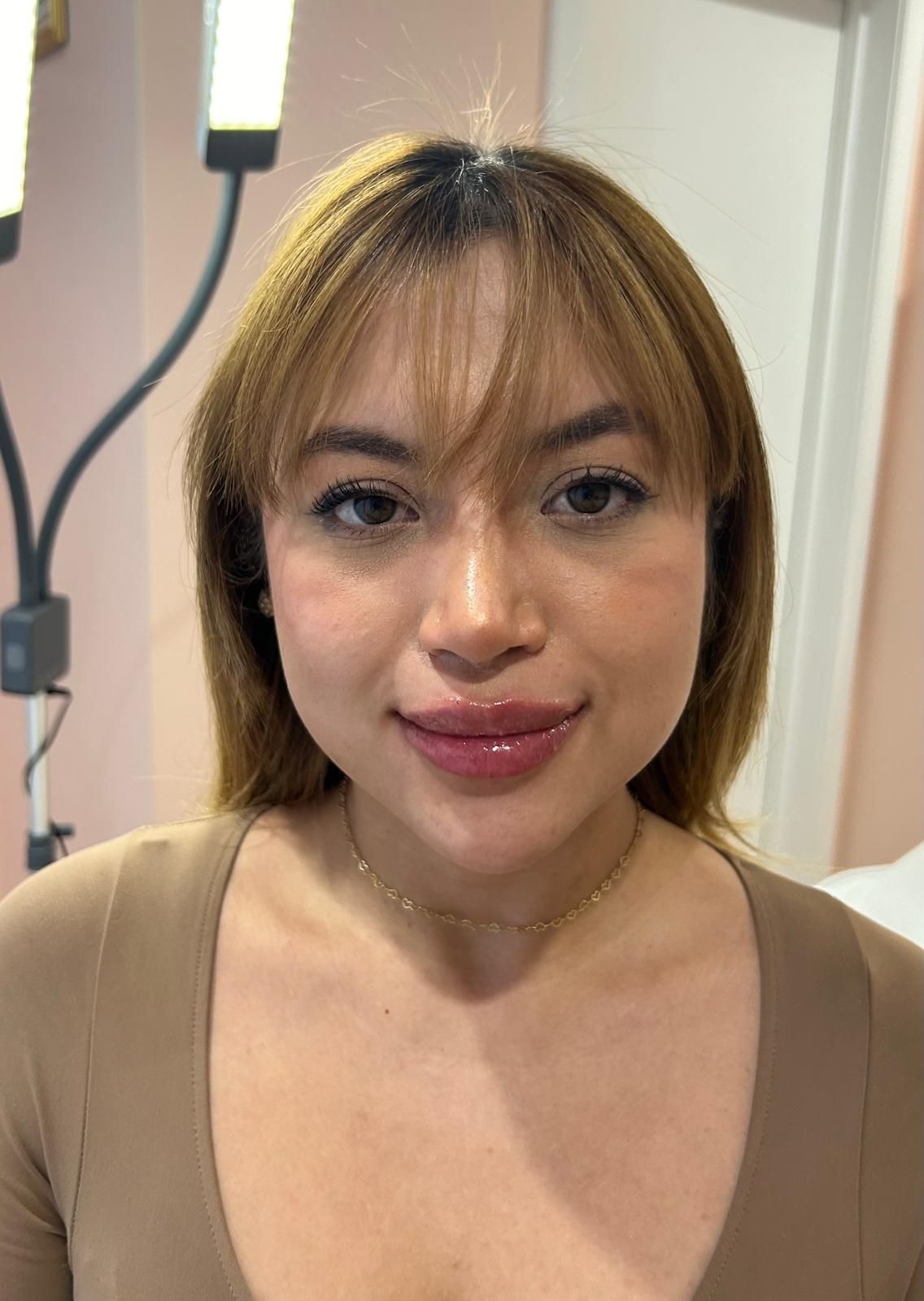 A woman with blonde hair and bangs after undergoing aesthetic service