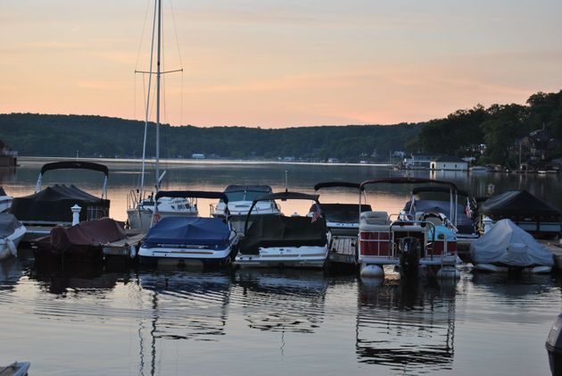 Boats moored at a calm marina at sunset, with pink sky and still water reflections