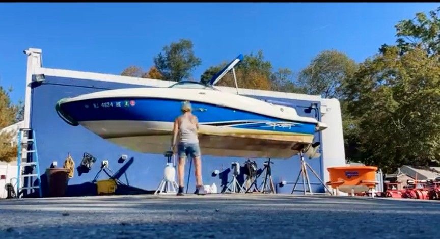 Blue-and-white speedboat on a lift, with people gathered around on a sunny outdoor dock
